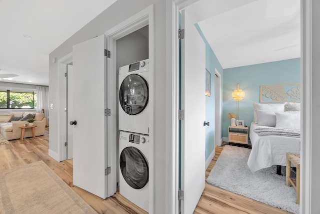 laundry room with stacked washer / dryer and light hardwood / wood-style floors