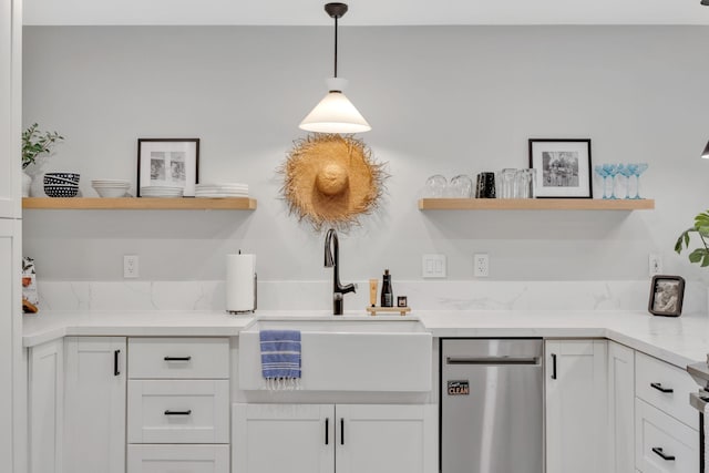 kitchen with light stone countertops, decorative light fixtures, white cabinetry, and sink