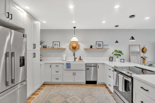 kitchen featuring sink, white cabinetry, hanging light fixtures, and appliances with stainless steel finishes