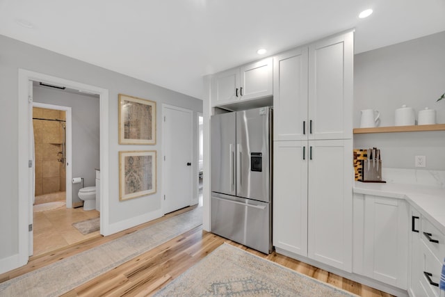 kitchen with light hardwood / wood-style floors, white cabinetry, and stainless steel fridge with ice dispenser