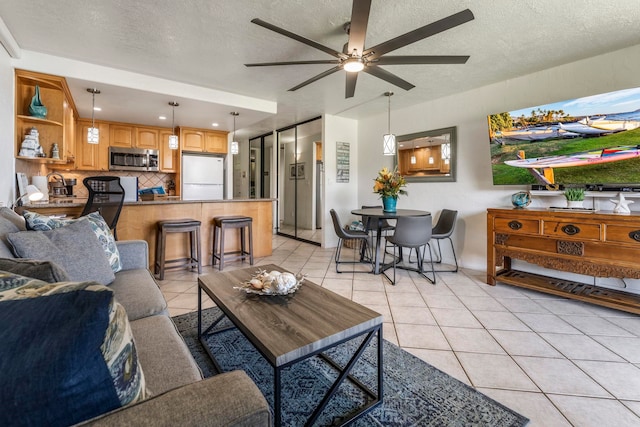 tiled living room with ceiling fan, sink, and a textured ceiling