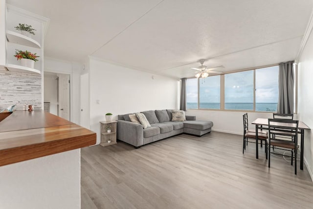 living area featuring light wood-style floors, a water view, and ceiling fan