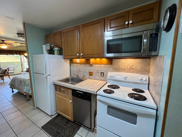 kitchen featuring tile countertops, stainless steel appliances, sink, light tile patterned floors, and tasteful backsplash