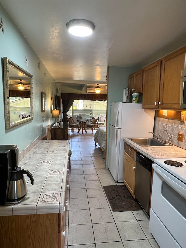 kitchen with tile countertops, stainless steel appliances, decorative backsplash, and sink