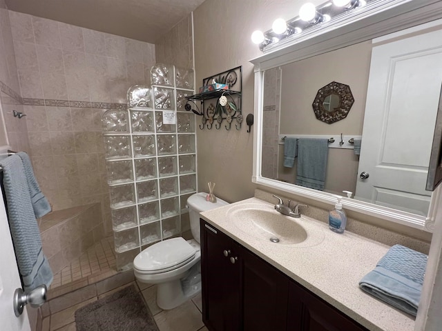 bathroom with vanity, a tile shower, toilet, and tile patterned floors