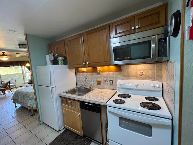 kitchen with decorative backsplash, appliances with stainless steel finishes, tile countertops, light tile patterned flooring, and sink