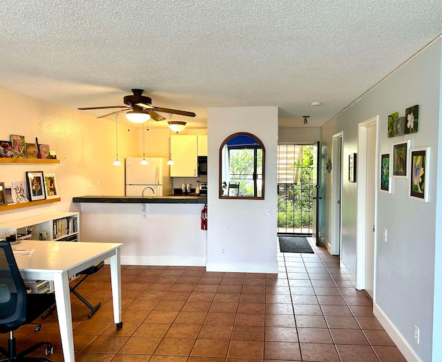 kitchen featuring dark tile patterned flooring, a kitchen breakfast bar, ceiling fan, white fridge, and kitchen peninsula