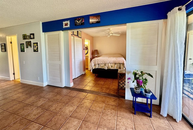 bedroom with a textured ceiling, tile patterned floors, and ceiling fan