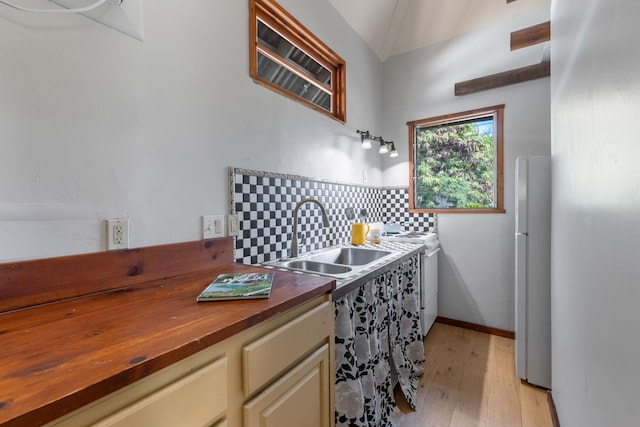 kitchen featuring white appliances, backsplash, cream cabinets, sink, and butcher block counters