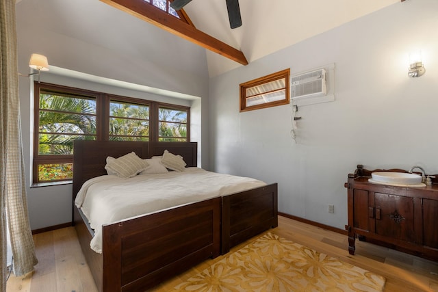 bedroom with a wall unit AC, multiple windows, ceiling fan, and vaulted ceiling with beams