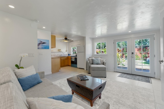 tiled living room featuring ceiling fan, french doors, and sink