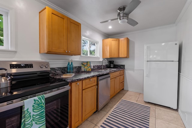 kitchen with appliances with stainless steel finishes, dark stone counters, crown molding, and sink