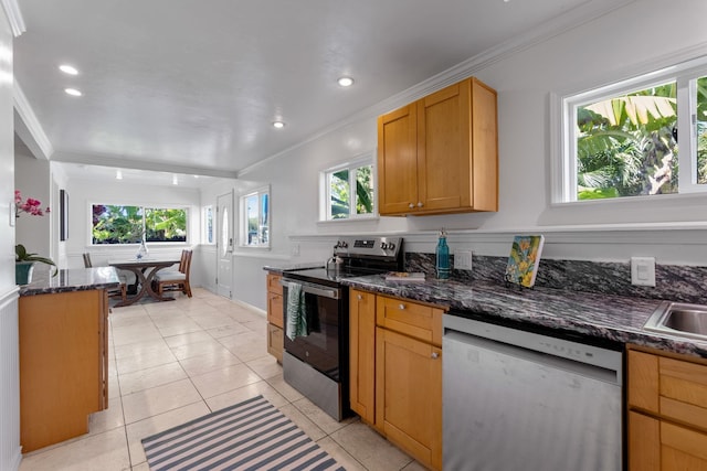 kitchen featuring dark stone countertops, light tile patterned floors, stainless steel appliances, and ornamental molding