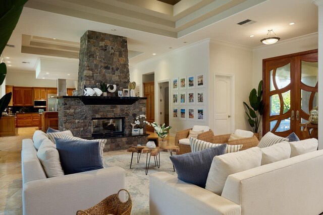 living area featuring a stone fireplace, crown molding, recessed lighting, and french doors