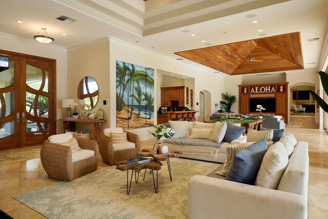 living room with visible vents, crown molding, a tray ceiling, french doors, and arched walkways