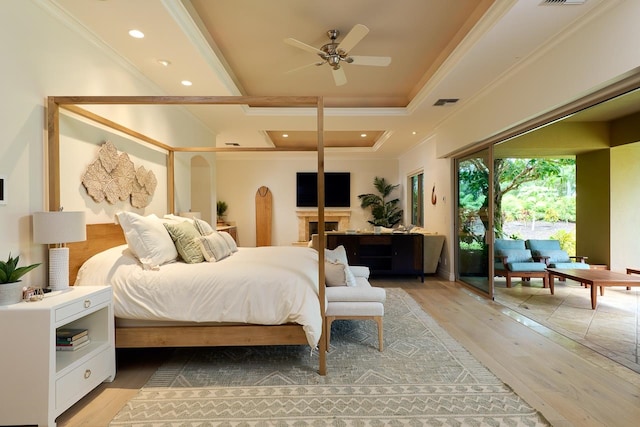 bedroom with crown molding, a raised ceiling, light wood-type flooring, access to exterior, and ceiling fan