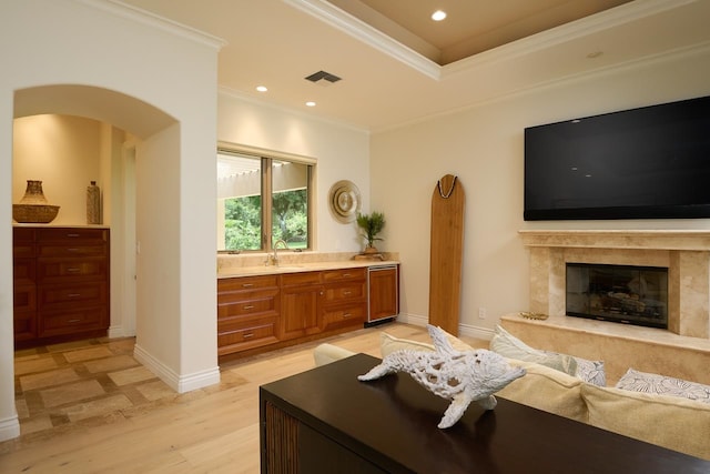 living room with sink, light hardwood / wood-style flooring, a high end fireplace, and ornamental molding