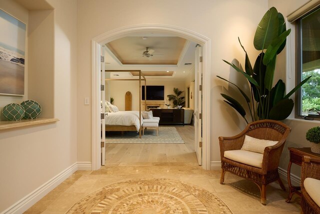 hallway featuring a raised ceiling and baseboards