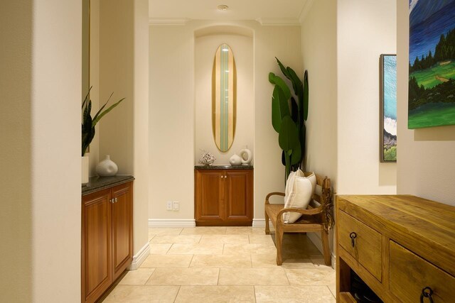 hallway featuring light tile patterned floors, baseboards, and ornamental molding