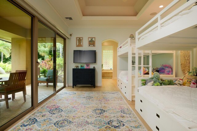 bedroom featuring visible vents, a tray ceiling, ornamental molding, light wood-style floors, and access to outside