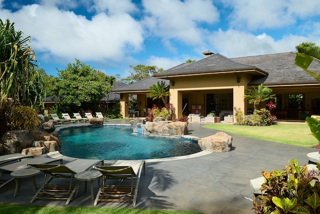 view of pool with a patio, a lawn, and pool water feature