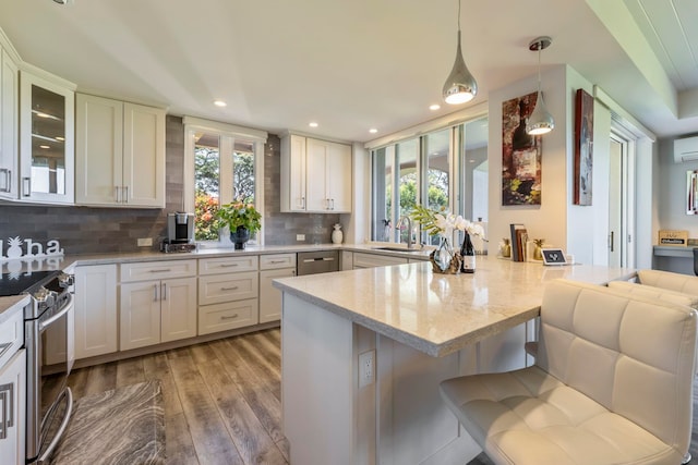 kitchen featuring kitchen peninsula, decorative light fixtures, light hardwood / wood-style floors, stainless steel electric range oven, and tasteful backsplash