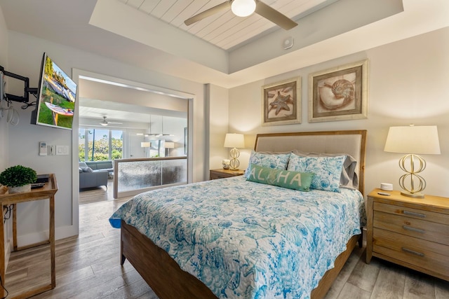 bedroom featuring ceiling fan, a tray ceiling, and hardwood / wood-style flooring