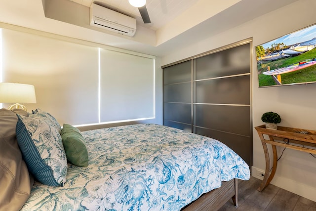 bedroom featuring wood-type flooring, a wall unit AC, ceiling fan, and a closet