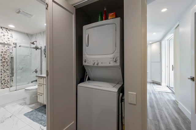 laundry area featuring light hardwood / wood-style flooring and stacked washer / drying machine