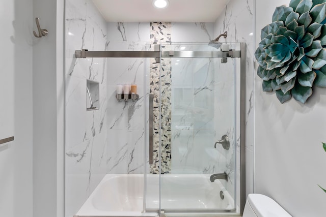 bathroom featuring toilet and bath / shower combo with glass door