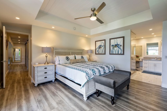 bedroom featuring connected bathroom, tile flooring, ceiling fan, and a raised ceiling