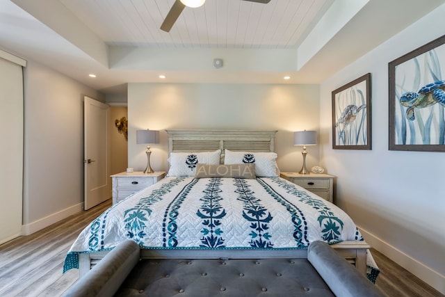 bedroom with a raised ceiling, ceiling fan, and hardwood / wood-style flooring