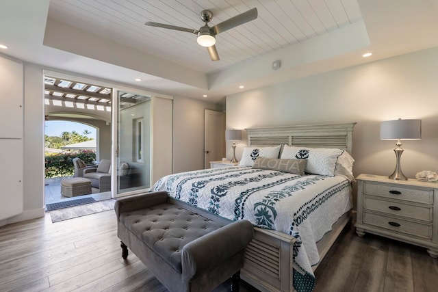 bedroom featuring ceiling fan, a raised ceiling, dark wood-type flooring, and access to exterior