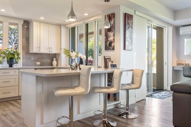 bar featuring backsplash, a wealth of natural light, pendant lighting, and light hardwood / wood-style floors