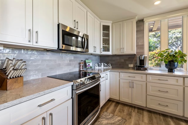 kitchen featuring light stone counters, white cabinets, tasteful backsplash, dark wood-type flooring, and stainless steel appliances