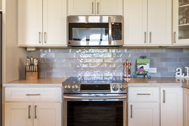 kitchen featuring tasteful backsplash, appliances with stainless steel finishes, and white cabinets