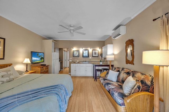 bedroom featuring freestanding refrigerator, crown molding, an AC wall unit, light wood-type flooring, and a sink