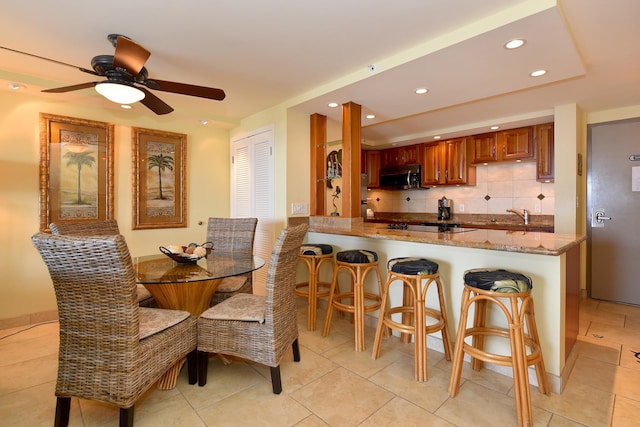 dining area with sink, ceiling fan, and light tile floors