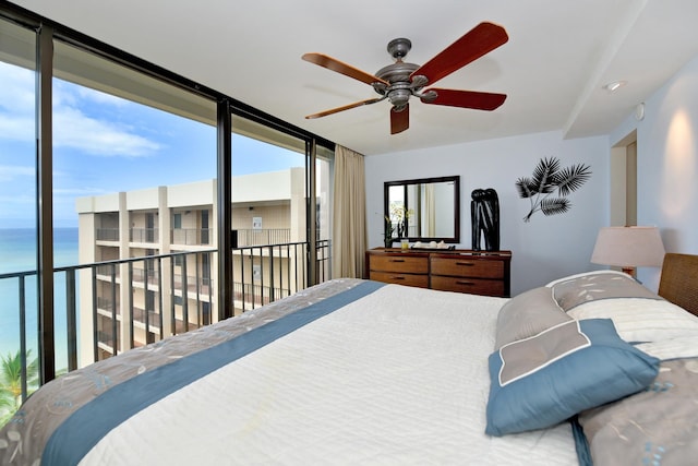 bedroom with ceiling fan, a water view, and a wall of windows