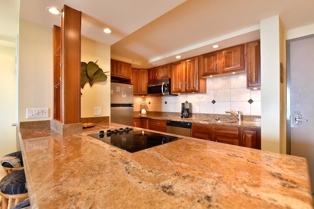 kitchen with sink, backsplash, a breakfast bar area, stainless steel appliances, and light stone countertops