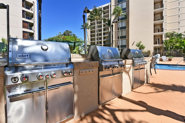 view of patio featuring an outdoor kitchen, a balcony, a grill, and a community pool