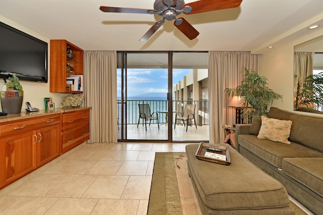 tiled living room featuring ceiling fan and a wall of windows