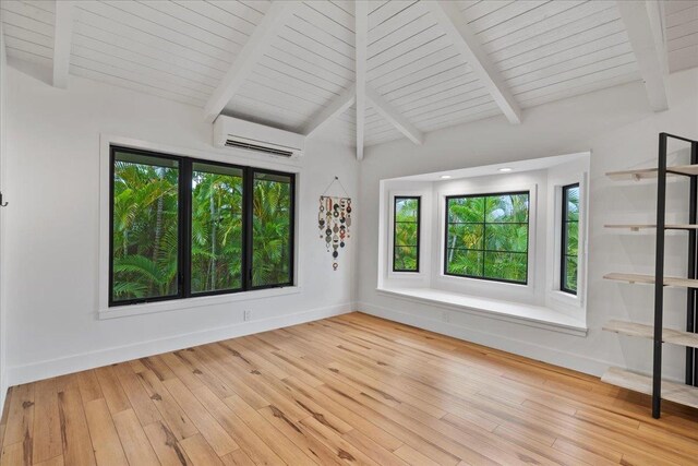 unfurnished room featuring a wall unit AC, plenty of natural light, and hardwood / wood-style flooring