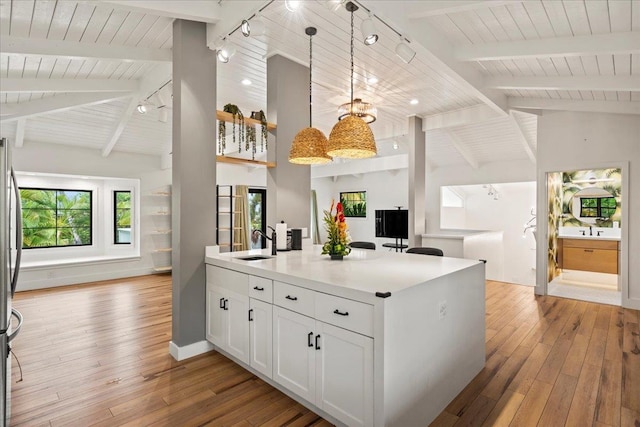 kitchen with open floor plan, light wood-style flooring, a sink, white cabinetry, and wooden ceiling