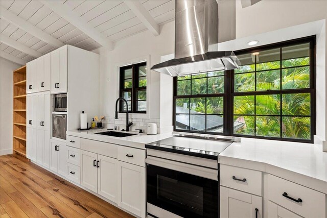 kitchen with a sink, electric range oven, wood ceiling, light countertops, and light wood-type flooring