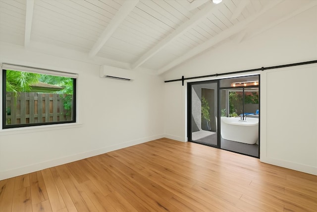 spare room featuring an AC wall unit, a barn door, baseboards, and light wood-type flooring