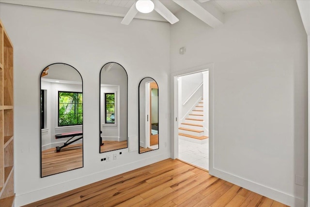 unfurnished room with light wood finished floors, a ceiling fan, baseboards, and stairway