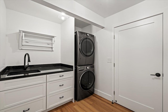 laundry room featuring stacked washer and clothes dryer and light wood-style floors