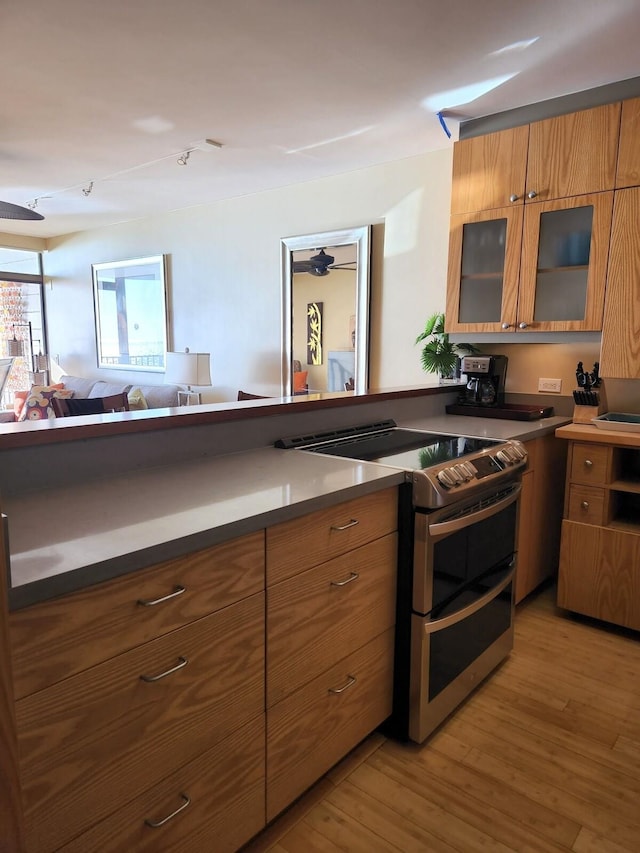 kitchen with ceiling fan, light wood-type flooring, and double oven range