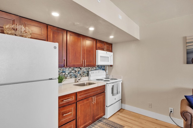 kitchen with baseboards, light countertops, light wood-style floors, white appliances, and a sink